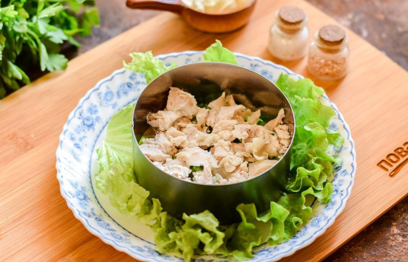 1. Этап. Салат Буррито: Подготовить салатник, для красоты можно выложить на тарелку салатный лист. Поставьте в центре тарелки кулинарное кольцо. Куриное филе нарежьте произвольно, выложите первым слоем.