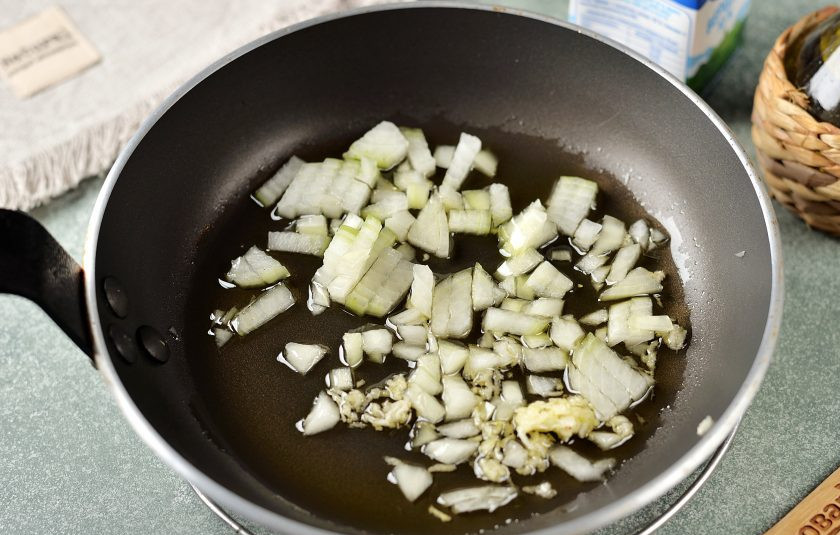 1. Этап. Морепродукты в сливочном соусе: Разогрейте в сковороде растительное масло, выложите в него нарезанный мелким кубиком лук и измельченный чеснок, обжарьте пару минут до мягкого состояния.