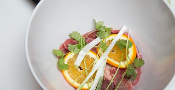 1. Этап. Карне асада из говядины: На дно миски уложите часть мяса, апельсин, зелени.