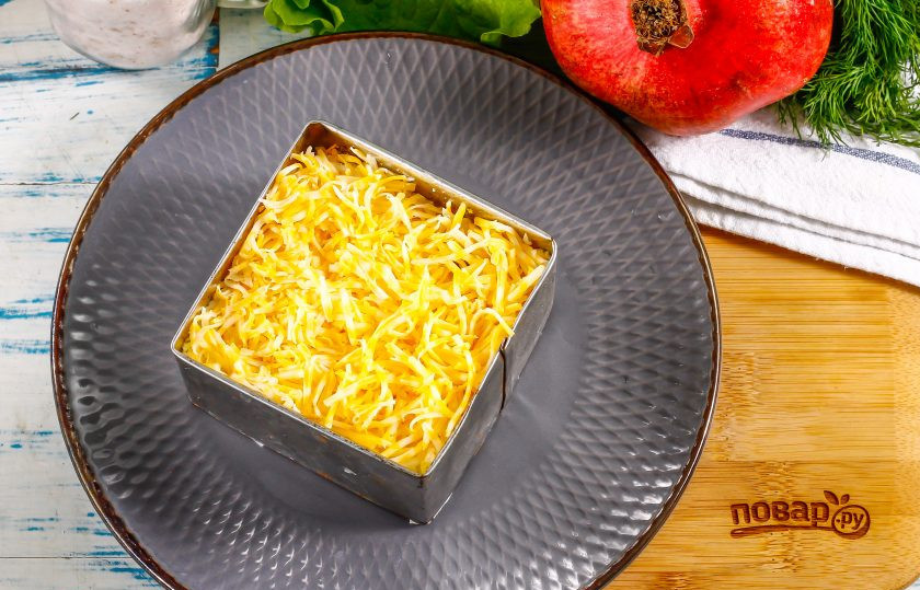 1. Этап. Салат Мужские слезы с гранатом: На этой же терке натрите и твердый сыр, выложите его на слой отварных куриных яиц и смажьте майонезом.