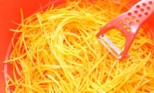 1. Этап. Салат из огурцов и морковки на зиму: Специальной овощечисткой нарезаем морковь соломкой по-корейски.