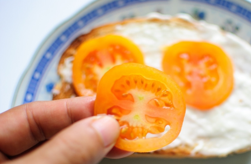 1. Этап. Сэндвич с колбасой: На один ломтик хлеба сложите сначала помидоры, нарезанные кружочками.