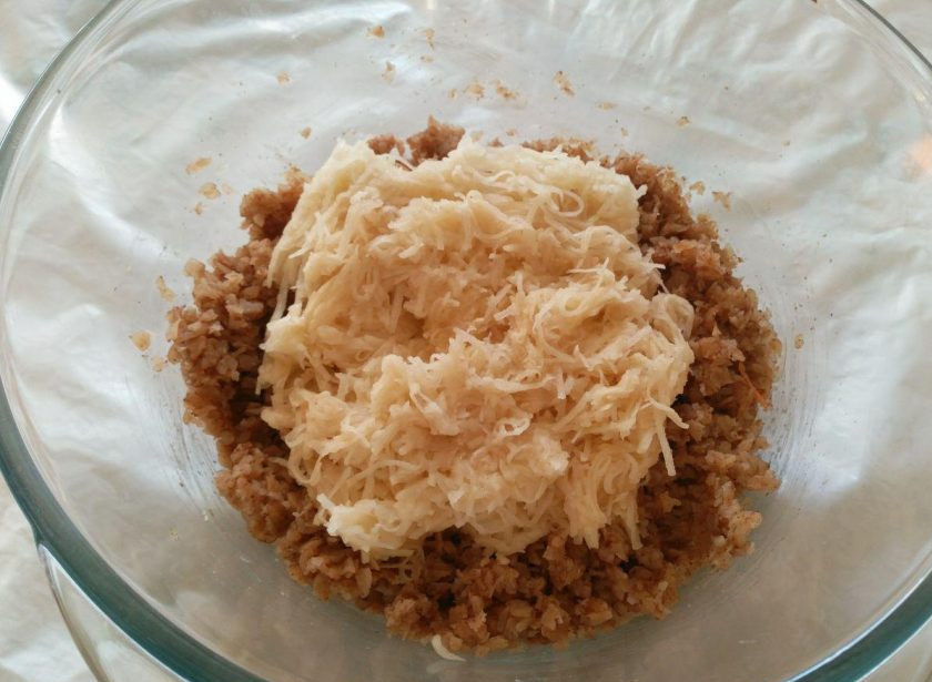 1. Этап. Гречневые зразы: Пока остывает начинка, завершите приготовление основы для зраз: натрите очищенный сырой картофель на мелкой тёрке и добавьте к настоявшимся хлопьям.