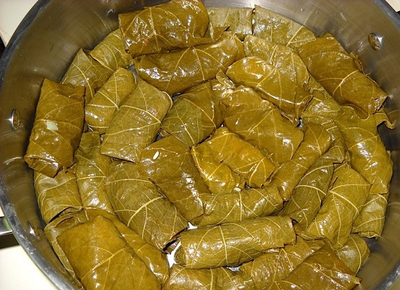 1. Этап. Постная долма (без мяса): 5. Выложите долму швом вниз на дно кастрюли, затем уложите поверх оставшиеся листья. Полейте оставшимся растительным маслом, залейте водой, чтобы только покрыть долму.