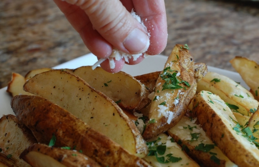 1. Этап. Закуска к пиву из картофеля: Готовый картофель достаем из духовки, посыпаем свежей петрушкой и мелко тертым пармезаном.