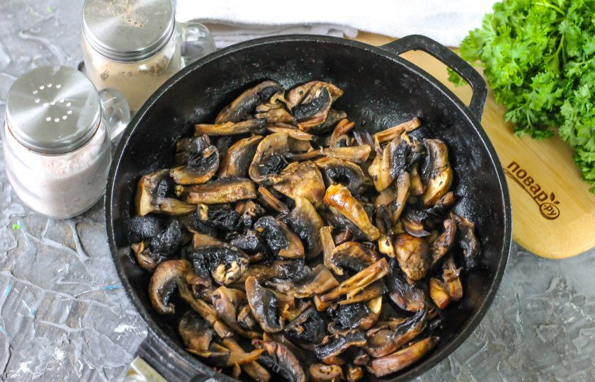 1. Этап. Закусочный торт Наполеон с курицей и грибами: Шампиньоны промойте в воде, обсушите бумажным полотенцем и нарежьте слайсами. Обжарьте грибную нарезку в растительном масле около 8-10 минут, предварительно посолив ее. Обязательно остудите!