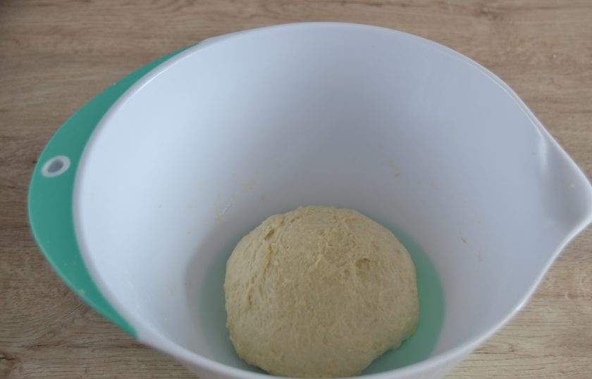 1. Этап. Батон на кефире: Всыпьте оставшуюся муку, замесите тесто, соберите его в комок. Смажьте стенки миски растительным маслом, накройте пищевой пленкой, оставьте на 1 час для подъема.