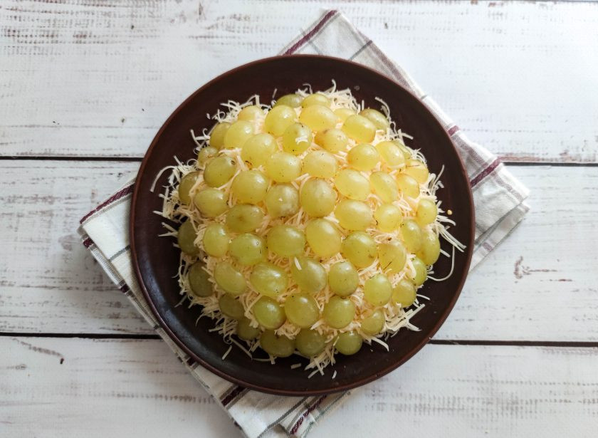 1. Этап. Салат Броненосец: Виноград хорошо помойте, разрежьте пополам и украсьте салат по всей поверхности.