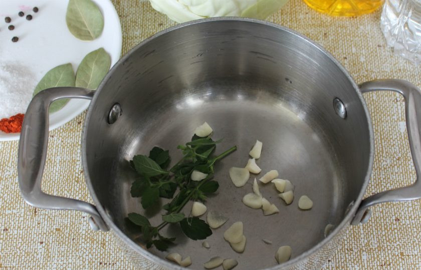 1. Этап. Заварная капуста на зиму: В кастрюлю кладем веточку мяты и нарезанный кусочками чеснок.