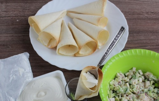 1. Этап. Праздничная закуска в тортилье: В остывший кулечек выложите чайную ложку творожного сыра.