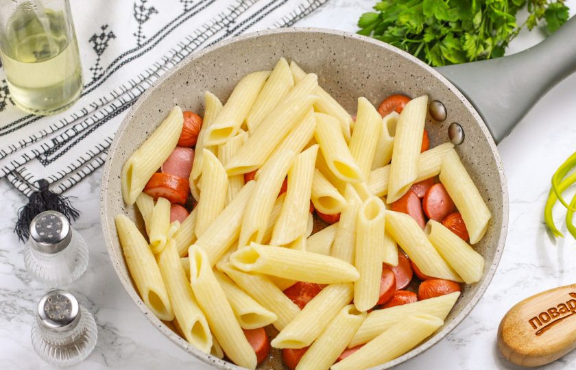 1. Этап. Макароны с сосисками на сковороде: Слейте бульон с макарон и выложите их на сковороду к сосискам.