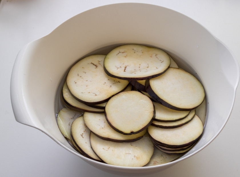 1. Этап. Мусака классическая: Нарежьте баклажаны кольцами и замочите в холодной воде с солью на 30-40 минут. Это необходимо, чтобы из овоща вышла вся горечь.