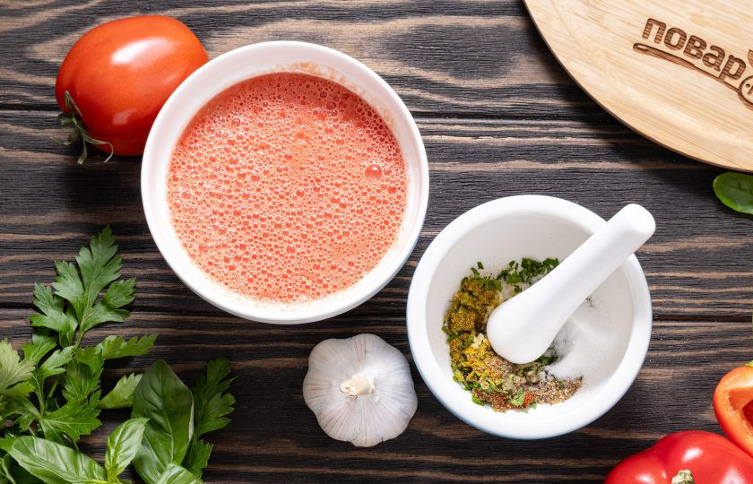 1. Этап. Аджапсандал с баклажаном и чесноком: В ступке разотрите измельченный чеснок с кинзой, всеми специями и солью. Помидоры ошпарьте кипятком, очистите от кожуры и измельчите блендером до состояния пюре.