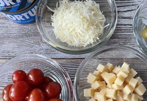 1. Этап. Холодная паста с тунцом: Подготовьте продукты для пасты. Оливки нарежьте колечками, твердый сыр натрите на мелкой терке (отлично подойдет пармезан). Сыр, который помягче, нарежьте ровными кубиками.