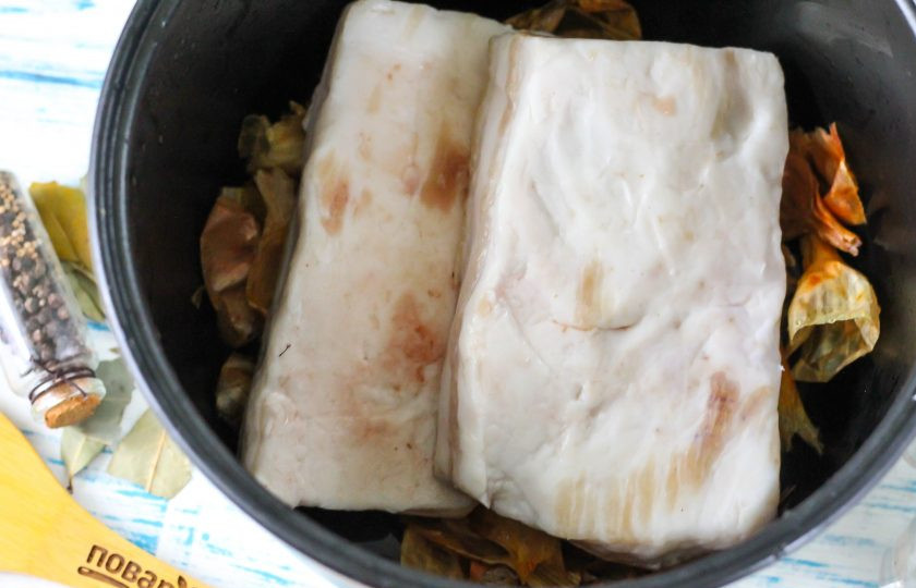 1. Этап. Сало в луковой шелухе в мультиварке: Луковую шелуху тщательно промойте и выложите на дно чаши мультиварки. Затем промойте свиное сало, соскоблите кожу ножом. Выложите куски сала прямо на шелуху.