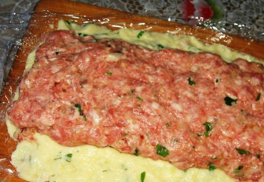 1. Этап. Мясной рулет в картофельной оболочке: На сковороде обжариваем мелко порубленные лук и чеснок. Добавляем фарш, манную крупу, кориандр. Затем вбиваем в эту смесь яйцо, добавляем сухарики и петрушку (мелко порезанную). Обжаренную массу выкладываем поверх картофельного слоя.