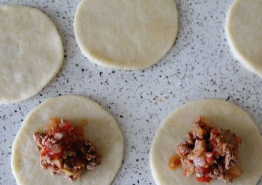 1. Этап. Маленькие пирожки с мясом: 5. На рабочей поверхности раскатать тесто довольно тонко и вырезать небольшими выемками или стаканом, например, кружочки. В серединку выложить ложку обжаренного и немного остывшее фарша.