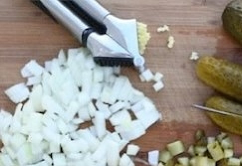 1. Этап. Вкусный салат Оливье: Чеснок и лук почистите и мелко нашинкуйте. Соленый огурец порежьте мелким кубиком.