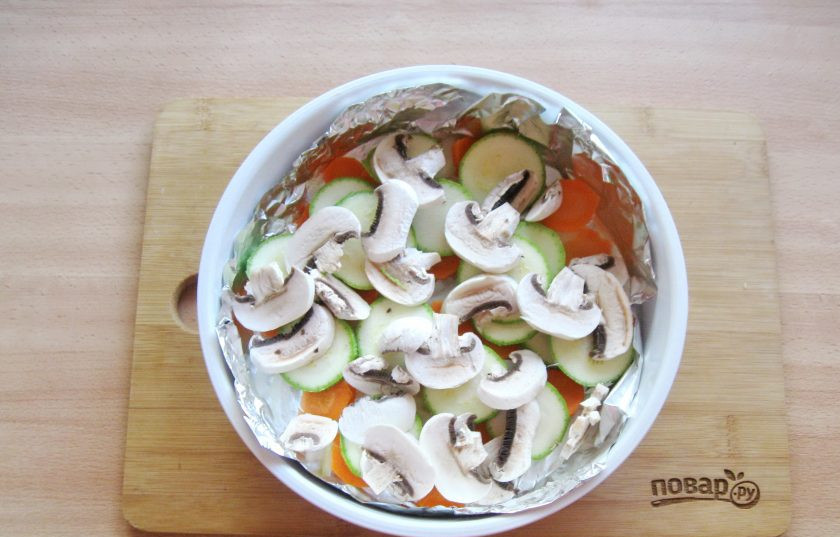 1. Этап. Скумбрия с овощами в пароварке: Кабачок и грибы помойте. Кабачок нарежьте кружками, а шампиньоны пластиночками. Выложите на лук с морковью. Немного посолите овощи.