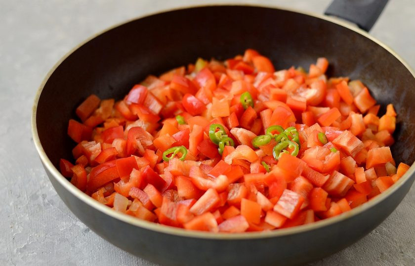 1. Этап. Армянский газаров перец: Болгарский перец помойте, удалите семена и хвостик, нарежьте кубиками, а острый перец колечками. Добавьте в сковороду, тушите все вместе 5-6 минут.