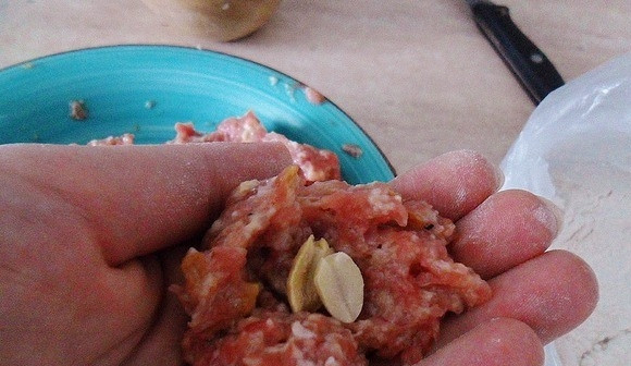 1. Этап. Биточки, запеченные под сметанным соусом: Руками сформируйте из получившейся массы шарики. В центр каждого положите по паре соленых орешков. В данном рецепте используется арахис, но вы можете взять фисташки или кешью.