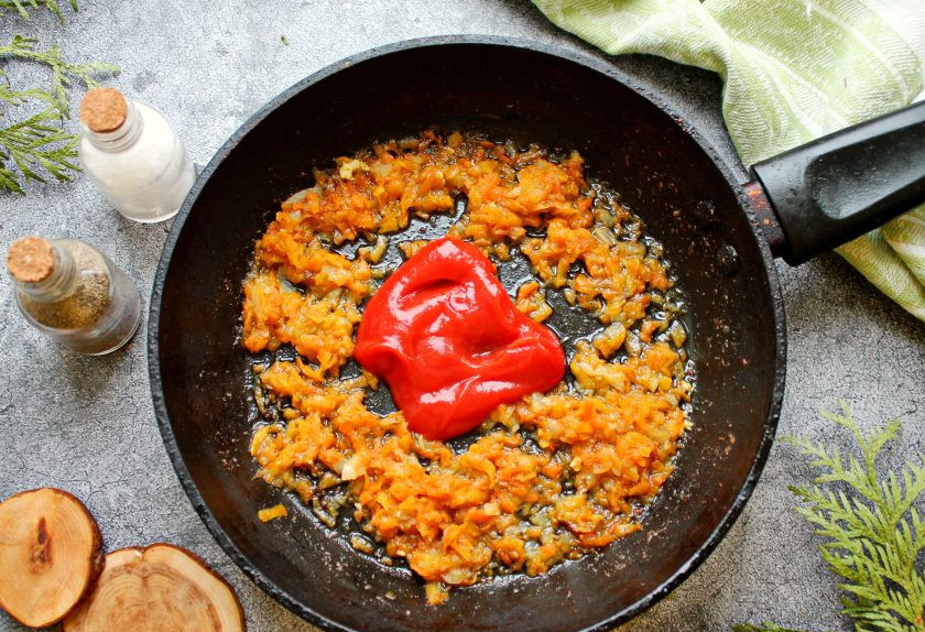 1. Этап. Куриные биточки в духовке с подливкой: В сковороду после биточков выложите мелко нарезанный лук и натертую на средней терке морковь. Обжаривайте овощи в течение 5 минут. Добавьте к овощам томатную пасту, муку, соль и перемешайте. Влейте в сковороду воду и доведите до кипения, мешая.