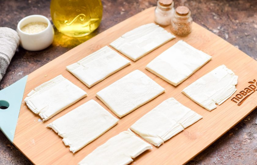1. Этап. Оливки в слоеном тесте: Слоеное тесто раскатайте тонким пластом. Разрежьте тесто на небольшие квадратики или прямоугольники.