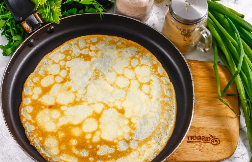 1. Этап. Блинчики с кальмарами: В блинное тесто влейте растительное масло и перемешайте его, испеките тонкие румяные блины по минуте на каждой стороне.