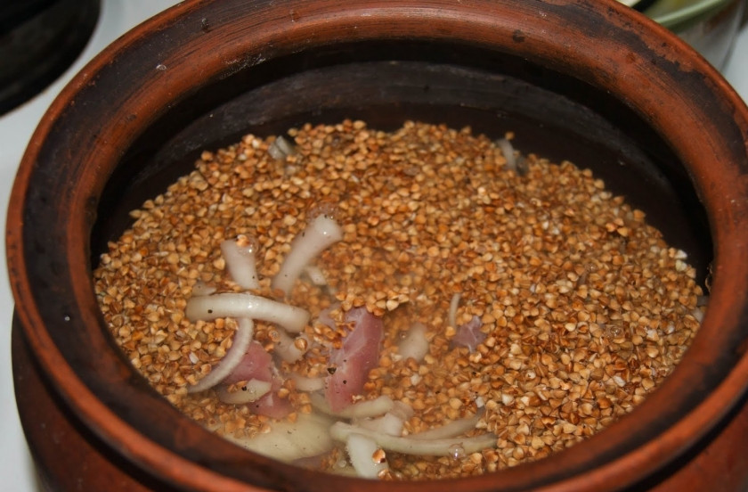 1. Этап. Гречка по-деревенски: Переложите мясо и лук в горшочек, сверху засыпьте промытой крупой. Посолите и залейте бульоном или водой. Накройте горшочек крышкой.