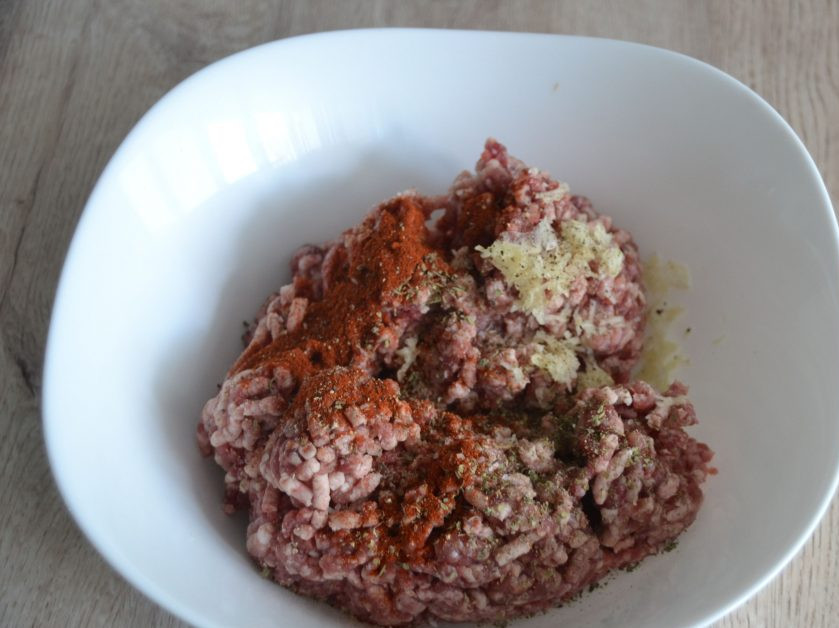 1. Этап. Чевапчичи по-сербски: Добавьте в фарш пряные травы, паприку, чеснок, посолите.