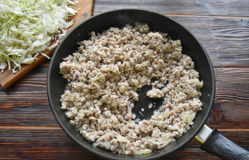 1. Этап. Пигоди по-корейски: В сковороде разогрейте растительное масло и начните пассеровать репчатый лук. Когда лук станет прозрачным и мягким, добавьте фарш и обжарьте на сильном огне до испарения лишней влаги.