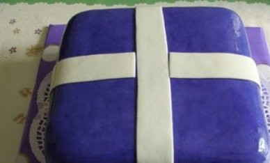 1. Этап. Торт Подарок: Из белой мастики вырезаем ленточки. Водой или водой с водкой протираем торт от остатков пудры или крахмала. Можно руками, можно мягкой широкой кистью и прикрепляем ленточки к торту.