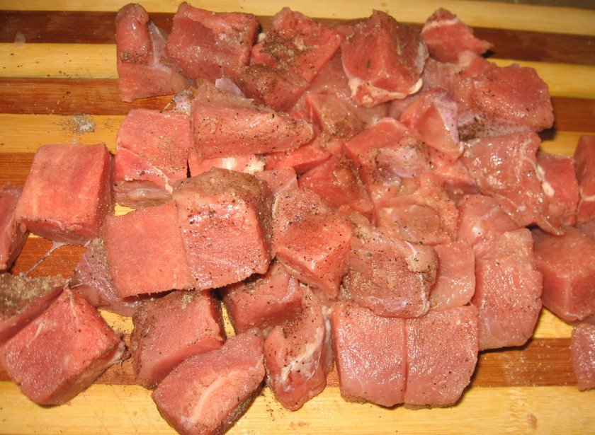 1. Этап. Гуляш из говядины с грибами: Говядину хорошенько промываем, затем высушиваем и нарезаем мясо небольшими кубиками (2,5 см шириной), посыпаем говядину солью и молотым перцем.