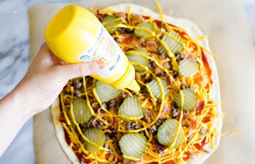 1. Этап. Начинка для пиццы с фаршем: 8. Маринованные огурцы нарежьте тонкими кружочками и распределите по всему пласту теста, полейте горчицей и кетчупом.