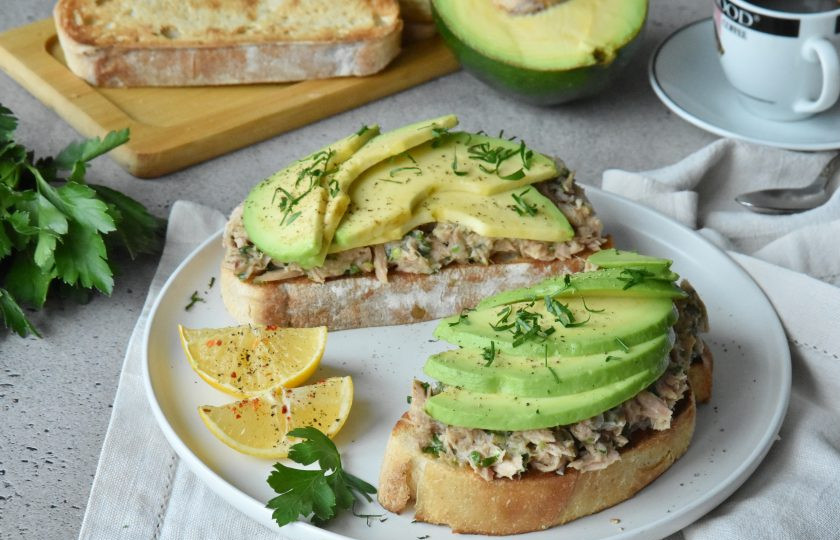1. Этап. Тост с авокадо и тунцом: На хлеб выложите щедрую порцию салатной смеси с тунцом. Сверху веером выложите дольки спелого авокадо. По желанию, дополнительно тост можно присыпать кунжутом и щепоткой молотого черного перца.