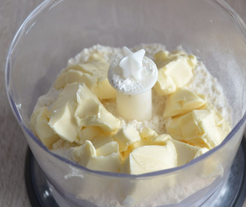 1. Этап. Тарталетки с лисичками: Первым делом очистите картофель, поставьте его отвариваться. Выложите в чашу блендера муку, разрыхлитель, соль и охлажденное сливочное масло нарезанное кубиком, измельчите в крошку.