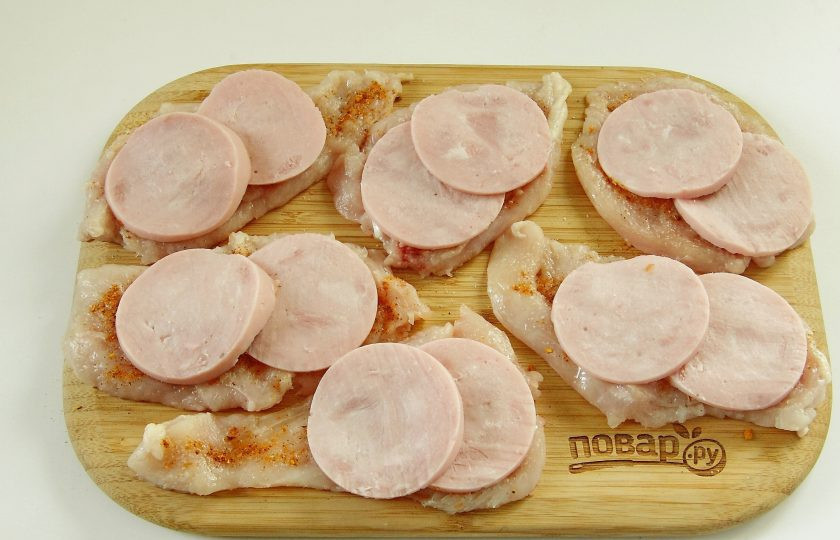 1. Этап. Куриные роллы с ветчиной и сыром: 3. Ветчину нарежьте максимально тонкими кружочками и выложите внахлест на отбитое филе по две штуки на порцию.