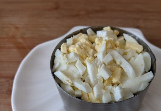 1. Этап. Салат Кудрявый Ваня: Следующим слоем кладём мелко-порезанное яйцо. Я использую яйцерезку. Слегка приминаем. Смазываем майонезом.