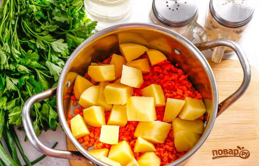 1. Этап. Суп с чечевицей и сосисками: Высыпьте промытую чечевицу в кастрюлю. Очистите картофель, лук и морковь от кожуры. Нарежьте картофель средними кубиками и добавьте в кастрюлю. Влейте горячую воду и поместите емкость на плиту, добавьте лавровые листья, соль и отварите все в течение 20 минут.