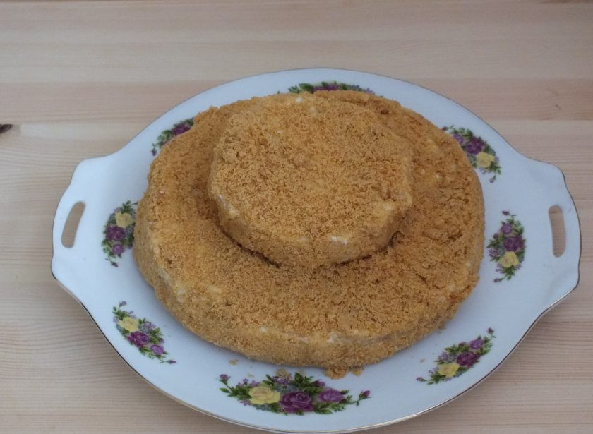 1. Этап. Торт Любава: Коржи слегка придавите, чтобы они соединились. Обсыпьте крошкой обе части и соедините большую часть с малой.