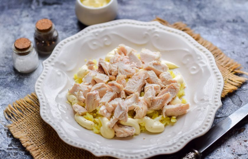 1. Этап. Салат с курицей и плавленным сыром: Отварное куриное филе нарежьте кусочками или разберите на волокна. Выложите филе поверх картофеля.