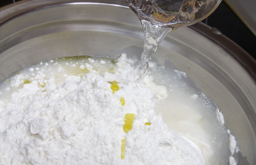 1. Этап. Фокачча бездрожжевая: Муку соедините с маслом, водой и солью. Замешайте тесто. Вымешивайте его в течение 7-10 минут.