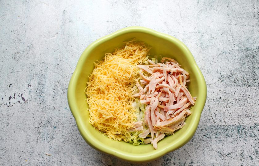 1. Этап. Салат Праздничный с говяжьим языком: Ветчину порежьте тонкой соломкой, сыр натрите на средней терке и добавьте в салат.