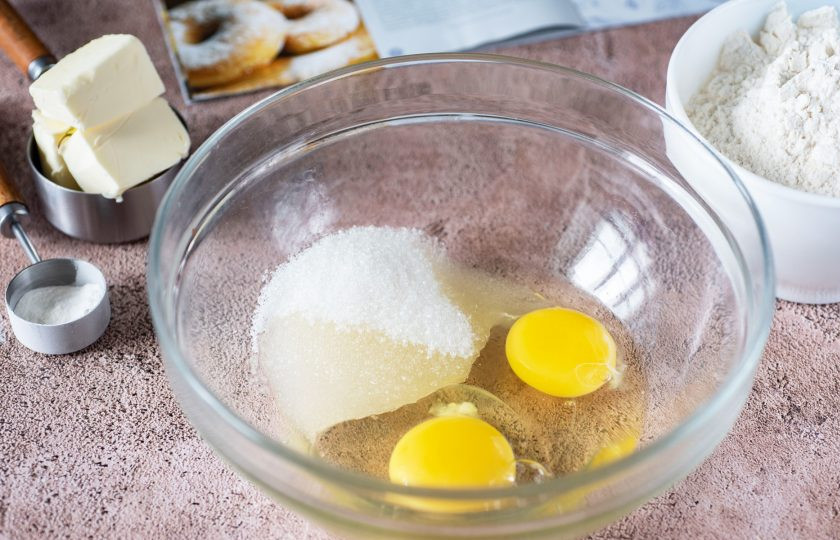 1. Этап. Пончики в мультипекаре: В просторную миску вбейте яйца и добавьте сахар.