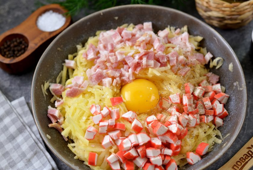 1. Этап. Драники с беконом и крабовыми палочками: Вбейте 1-2 яйца, всыпьте соль и перец по вкусу, добавьте немного муки для клейкости.