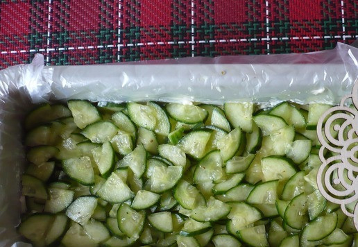 1. Этап. Салат рождественский Золотое полено: Нарежьте на четвертинки свежий огурец, посолите по вкусу (переложите на сито, чтобы стекла лишняя жидкость), а затем выложите на сырный слой, смажьте майонезом.