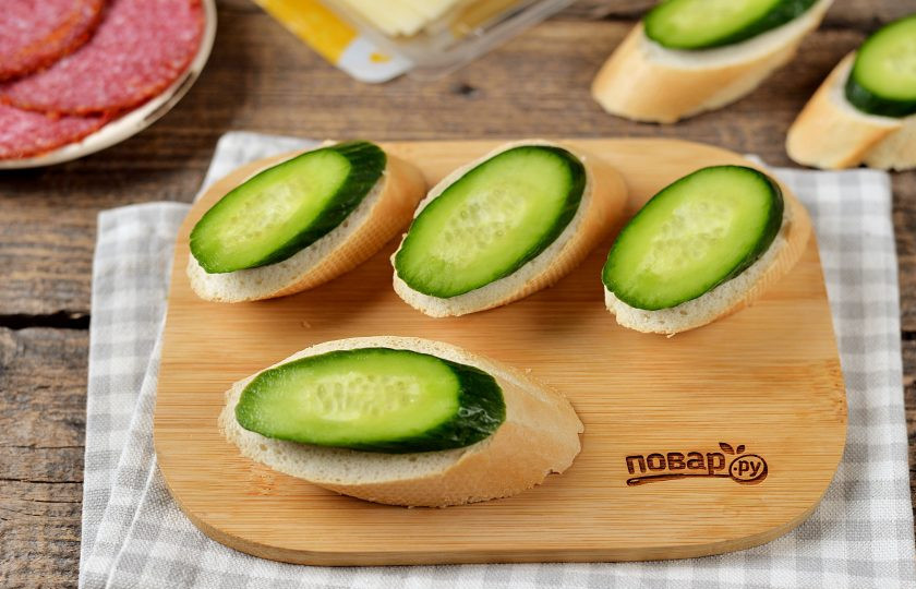 1. Этап. Канапе Кораблик: Нарежьте тонкий багет слегка наискосок толщиной в сантиметр. При желании хлеб можно смазать творожным или сливочным сыром, в крайнем случае — майонезом.