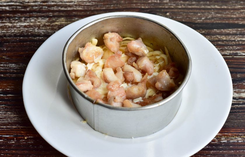 1. Этап. Салат Чебурашка с курицей: Сделайте сетку из майонеза и выложите на него сверху жареное мясо. Этот и последующие слои смазывайте майонезом.