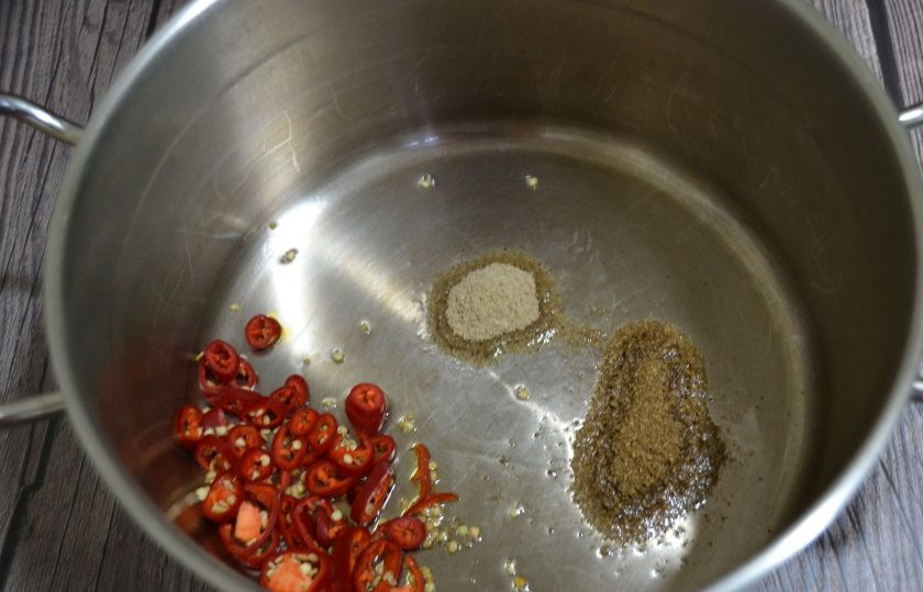 1. Этап. Чатни из слив на зиму: В кастрюлю или сотейник с толстым дном влейте растительное масло, всыпьте чили, кориандр и кардамон, размешайте, прогрейте.