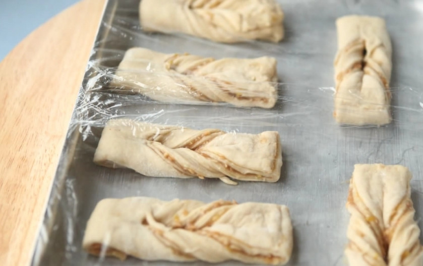 1. Этап. Миндальные бантики (слойки): 7. Сложите полосы на смазанном жиром противне с достаточным интервалом, накройте пленкой и оставьте в теплом месте на 20 минут.